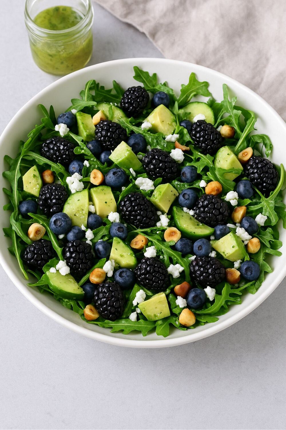 Brombeer-Avocado-Rucola-Salat mit Limetten-Minz-Vinaigrette Schale mit Rucolasalat, Brombeeren, Avocado, Gurken, Blaubeeren, Nüssen und Feta.