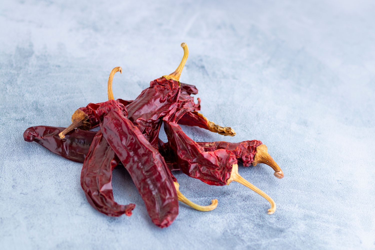 Chilipulver & Chili-Salz Haufen getrockneter roter Chilischoten auf hellgrauem Hintergrund.